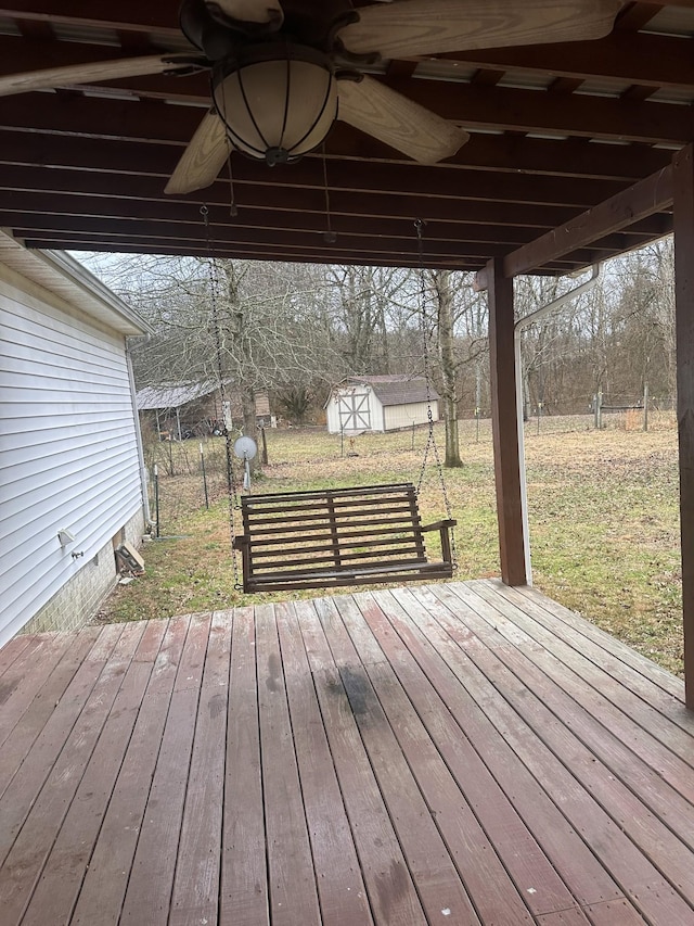 deck featuring ceiling fan, a shed, and a lawn