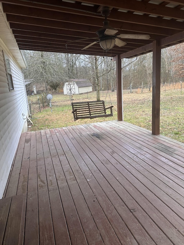 wooden deck featuring a yard, ceiling fan, and a storage shed