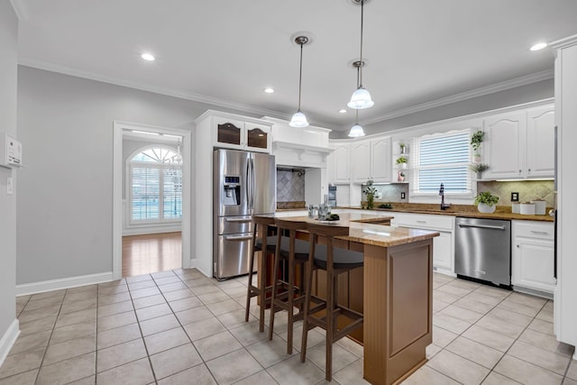 kitchen with light stone countertops, stainless steel appliances, a center island, and white cabinets