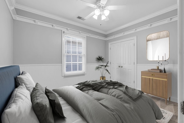 carpeted bedroom with crown molding, ceiling fan, and a closet