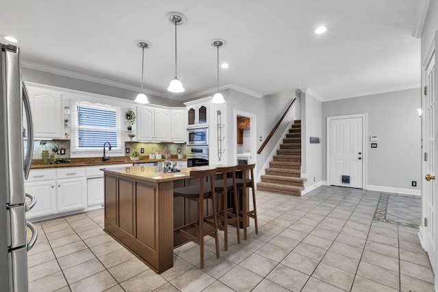 kitchen featuring a kitchen island, appliances with stainless steel finishes, sink, white cabinets, and light tile patterned floors