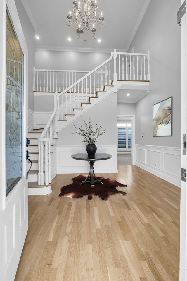 foyer entrance featuring a notable chandelier, crown molding, and light wood-type flooring