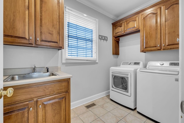 clothes washing area featuring sink, crown molding, cabinets, light tile patterned floors, and washing machine and dryer