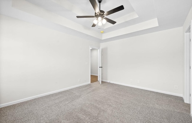 unfurnished room featuring a raised ceiling, carpet flooring, and ceiling fan