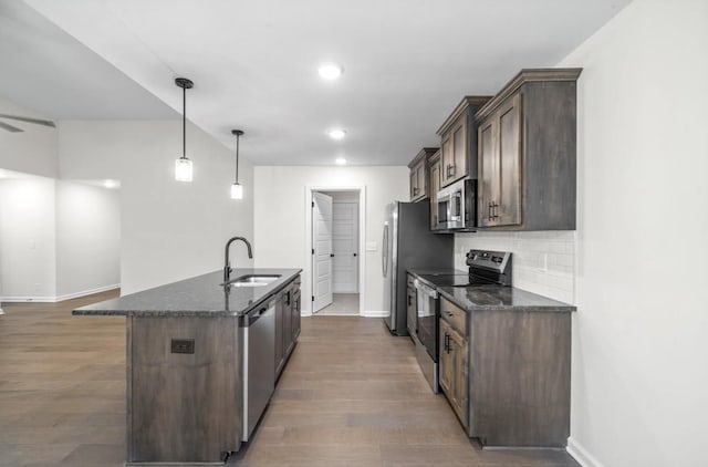 kitchen featuring dark brown cabinetry, sink, decorative light fixtures, dark stone countertops, and appliances with stainless steel finishes