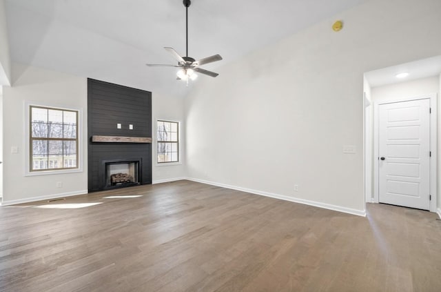 unfurnished living room featuring ceiling fan, a large fireplace, wood-type flooring, and high vaulted ceiling