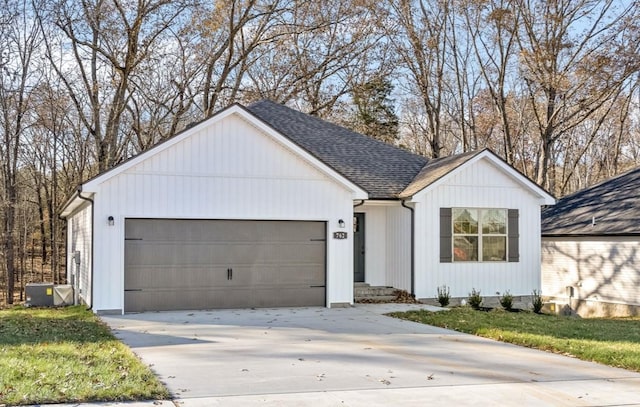 view of front of home featuring central AC unit, a garage, and a front lawn