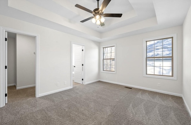 carpeted empty room featuring a raised ceiling and ceiling fan