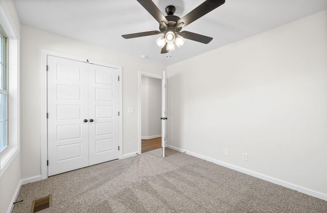 unfurnished bedroom featuring multiple windows, a closet, ceiling fan, and carpet