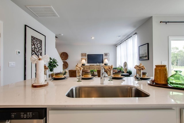 kitchen with light stone counters, stainless steel dishwasher, and sink