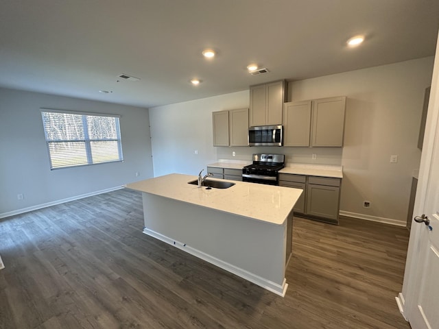 kitchen with sink, a center island with sink, gray cabinets, and appliances with stainless steel finishes