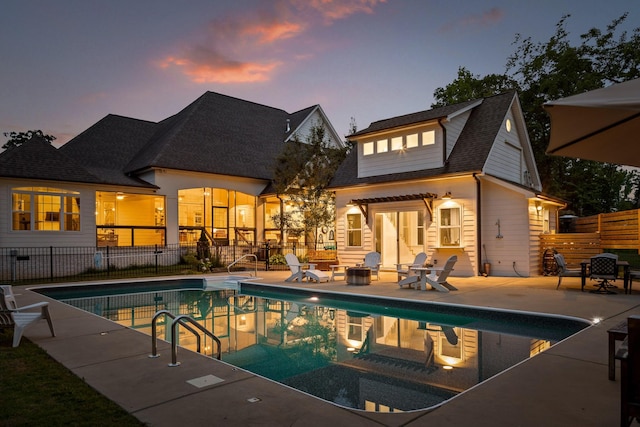 pool at dusk with a fire pit and a patio area