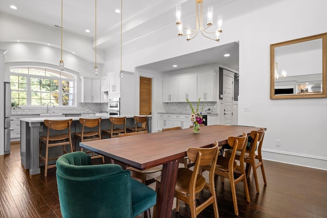 dining space with an inviting chandelier, sink, dark wood-type flooring, and a high ceiling