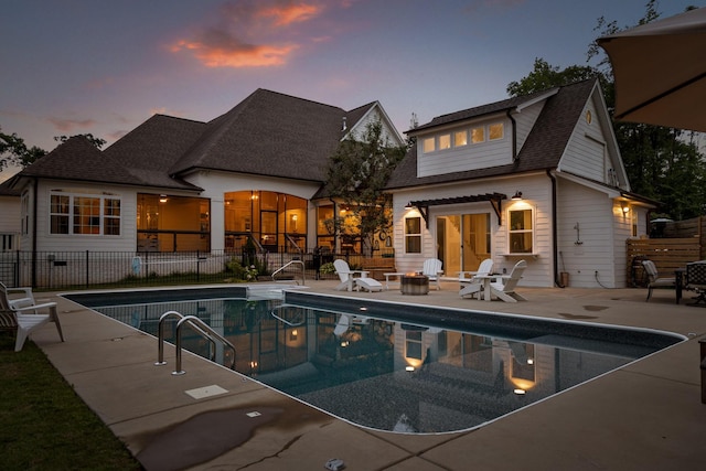 pool at dusk with a fire pit and a patio area