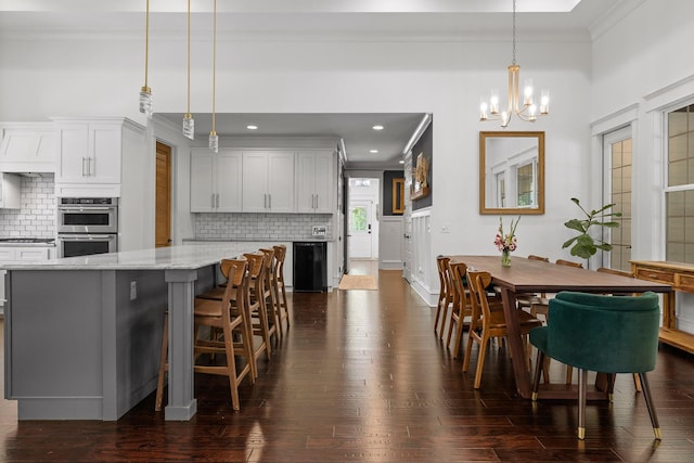 dining area with crown molding, dark wood-type flooring, and a notable chandelier