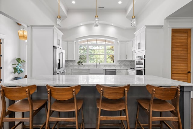 kitchen with stainless steel appliances, white cabinetry, pendant lighting, and backsplash