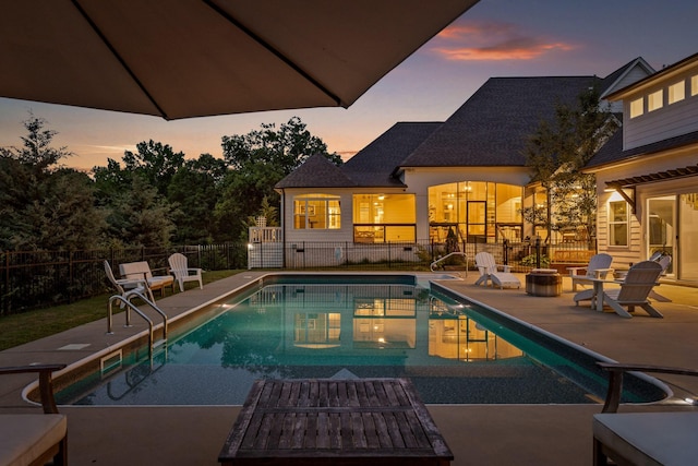 pool at dusk with a patio area