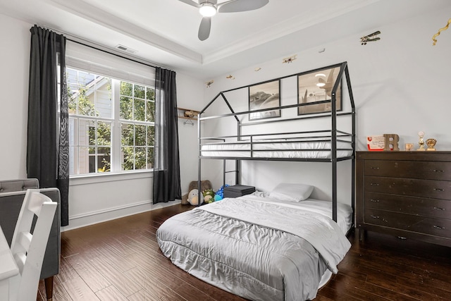 bedroom with wood-type flooring and a raised ceiling