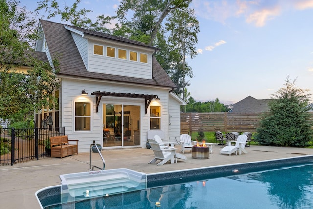 back house at dusk featuring an outbuilding, an outdoor fire pit, a fenced in pool, and a patio