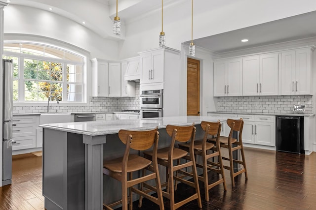 kitchen featuring stainless steel appliances, white cabinetry, hanging light fixtures, and a center island