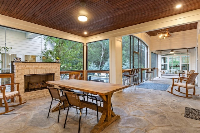 sunroom with wood ceiling, a chandelier, and a brick fireplace