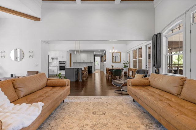 living room with an inviting chandelier, a towering ceiling, hardwood / wood-style floors, and beam ceiling