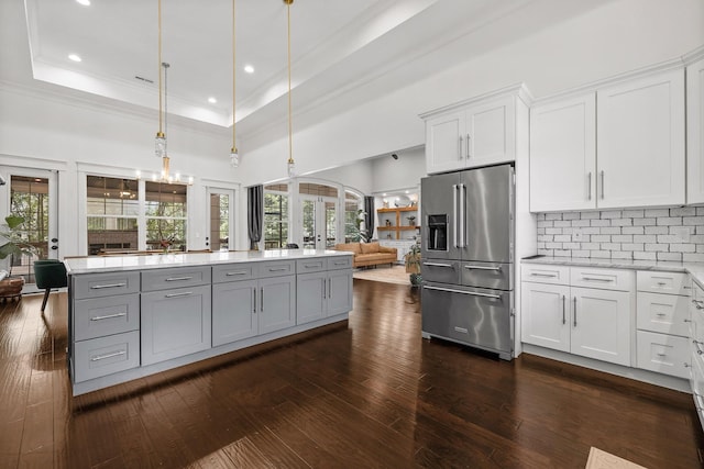 kitchen with dark hardwood / wood-style floors, pendant lighting, high end refrigerator, white cabinets, and a raised ceiling