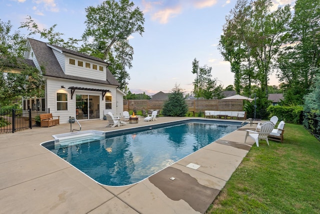 pool at dusk featuring a patio and a lawn