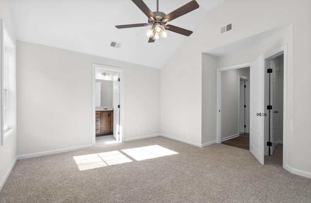 unfurnished bedroom featuring connected bathroom, vaulted ceiling, light colored carpet, and ceiling fan