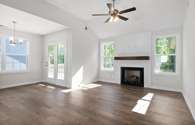 unfurnished living room featuring vaulted ceiling, ceiling fan with notable chandelier, dark hardwood / wood-style floors, and a wealth of natural light