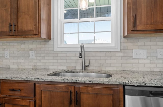 kitchen with tasteful backsplash, light stone countertops, sink, and stainless steel dishwasher