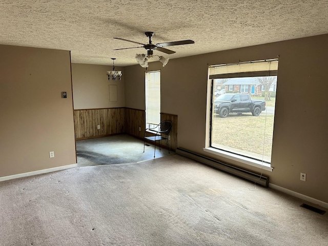 spare room featuring a baseboard heating unit, carpet floors, and a textured ceiling