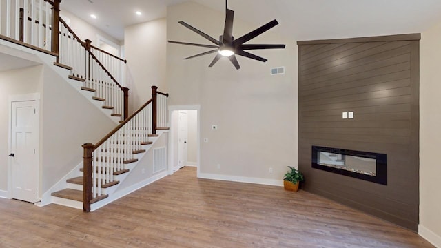 unfurnished living room with light wood-style floors, baseboards, visible vents, and a glass covered fireplace