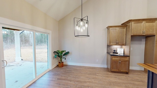 dining area featuring light wood-style floors, baseboards, and high vaulted ceiling