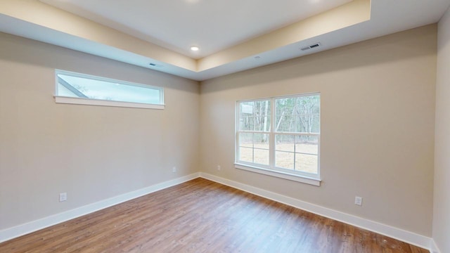 empty room with recessed lighting, wood finished floors, visible vents, and baseboards