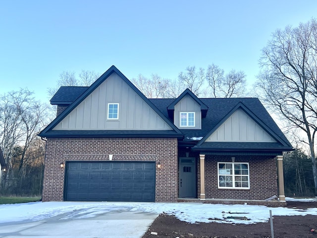 view of front facade with driveway, a shingled roof, an attached garage, board and batten siding, and brick siding