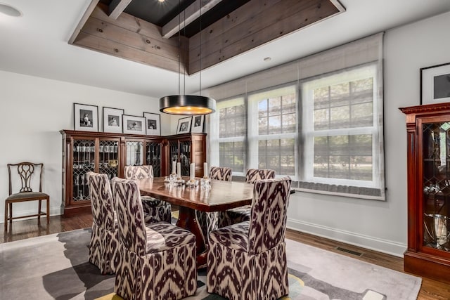 dining space featuring a raised ceiling and wood-type flooring