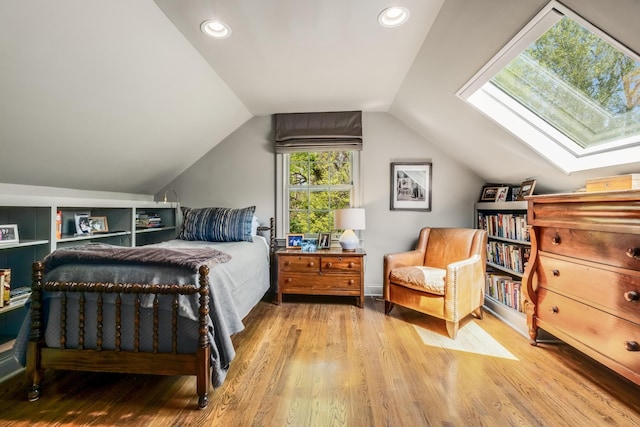 bedroom with lofted ceiling with skylight and light hardwood / wood-style floors