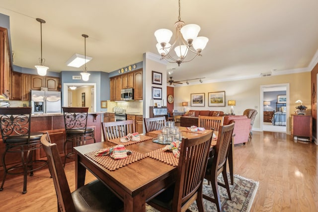 dining area featuring crown molding, light hardwood / wood-style flooring, rail lighting, and ceiling fan with notable chandelier