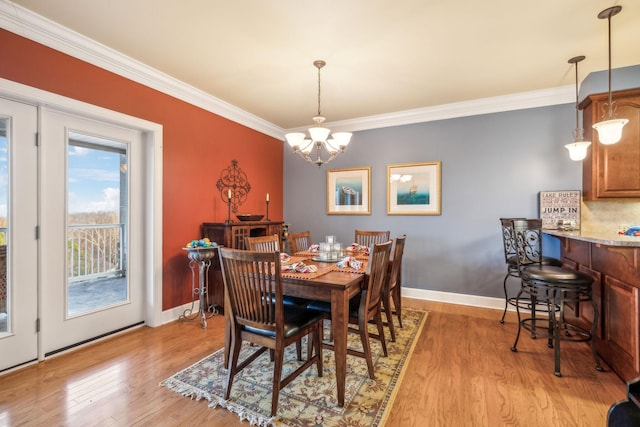 dining room featuring ornamental molding, a chandelier, and light hardwood / wood-style flooring