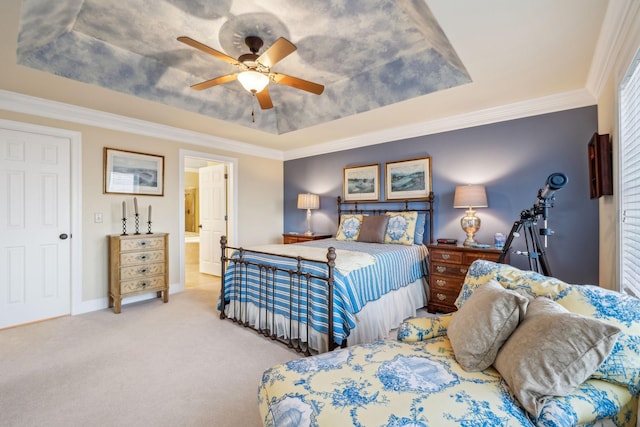 carpeted bedroom featuring crown molding, ensuite bath, a raised ceiling, and ceiling fan