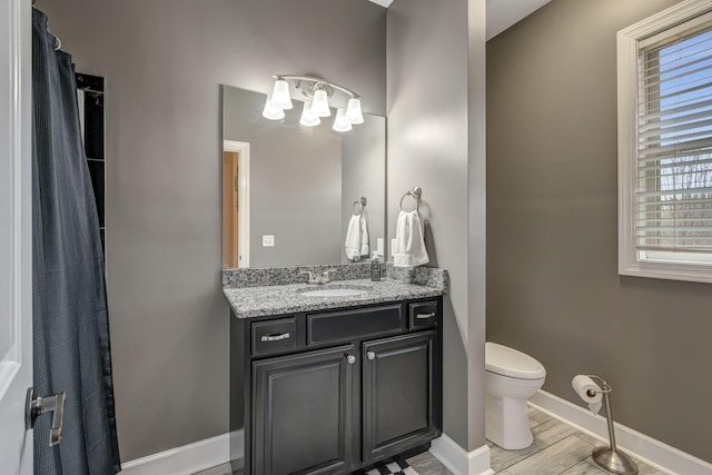 bathroom with hardwood / wood-style flooring, vanity, a healthy amount of sunlight, and toilet