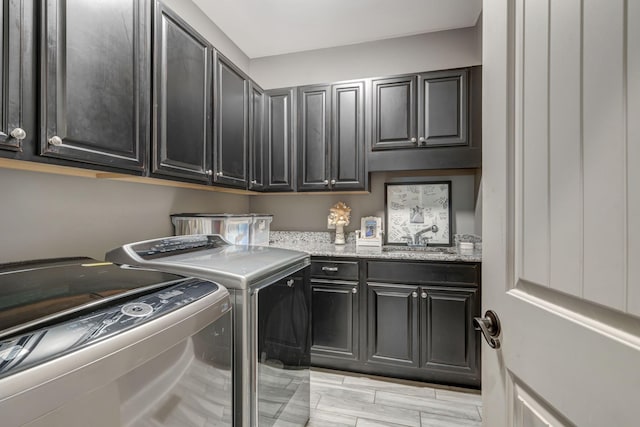 clothes washing area featuring cabinets, washer and clothes dryer, and sink