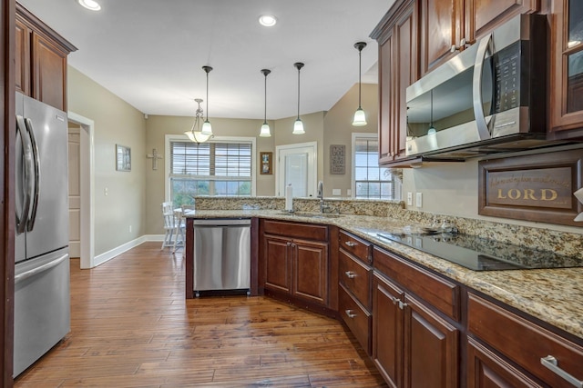 kitchen featuring dark hardwood / wood-style floors, pendant lighting, sink, light stone counters, and stainless steel appliances