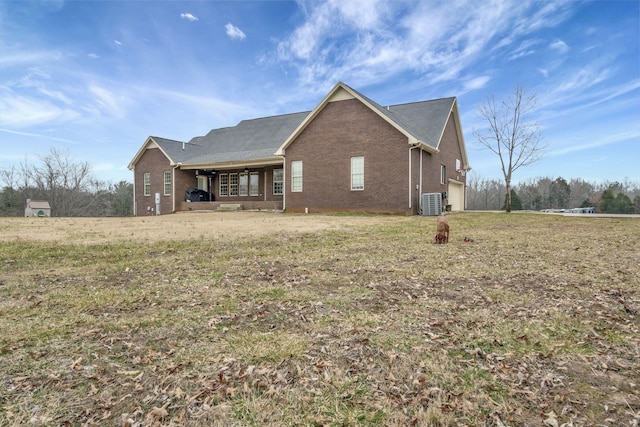 rear view of house with cooling unit and a yard