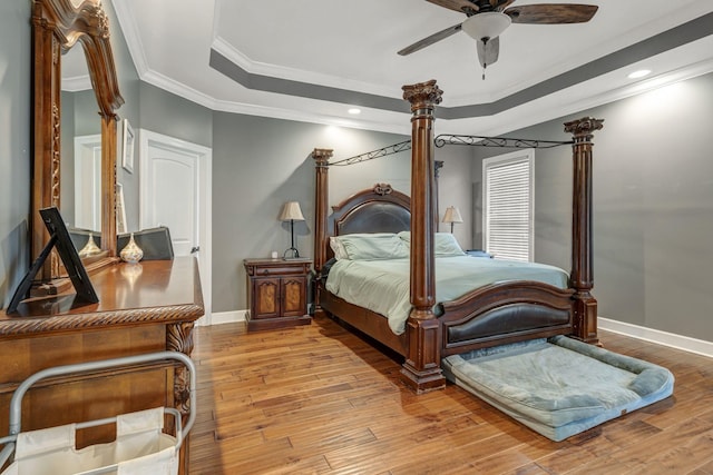 bedroom featuring crown molding, light hardwood / wood-style flooring, a raised ceiling, and ceiling fan