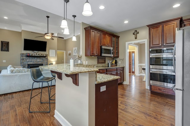 kitchen with dark wood-type flooring, a breakfast bar, appliances with stainless steel finishes, and kitchen peninsula