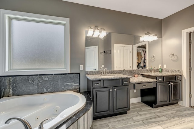 bathroom featuring a relaxing tiled tub and vanity