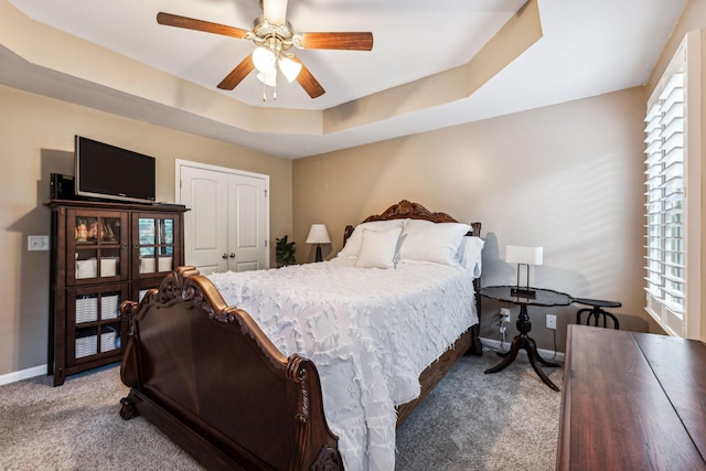 carpeted bedroom featuring ceiling fan, a raised ceiling, and a closet