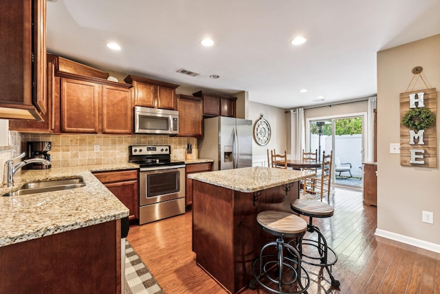 kitchen featuring sink, light stone countertops, a center island, and appliances with stainless steel finishes